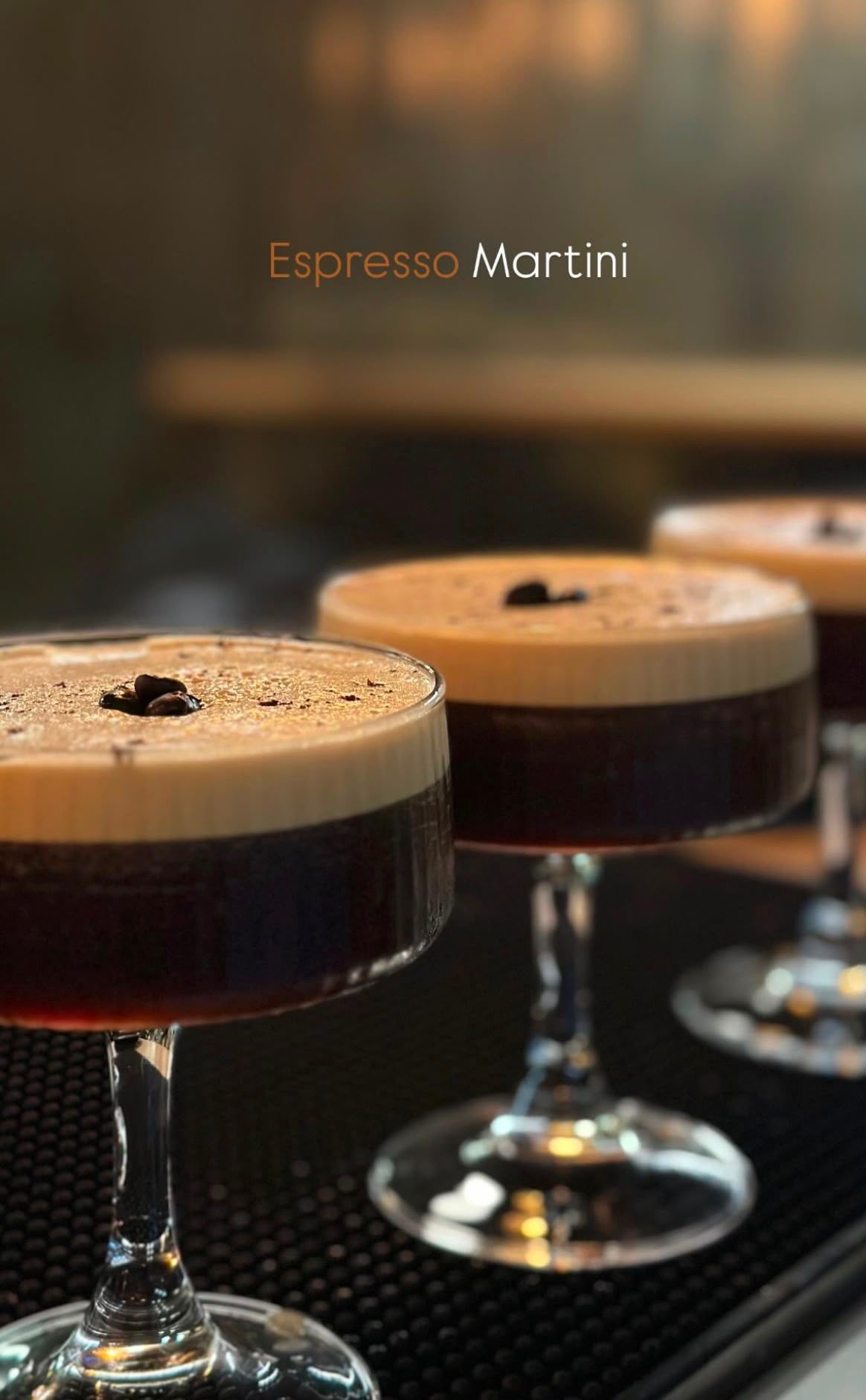 Copas coupe con Espresso Martini, espuma cremosa y granos de café decorando la superficie.