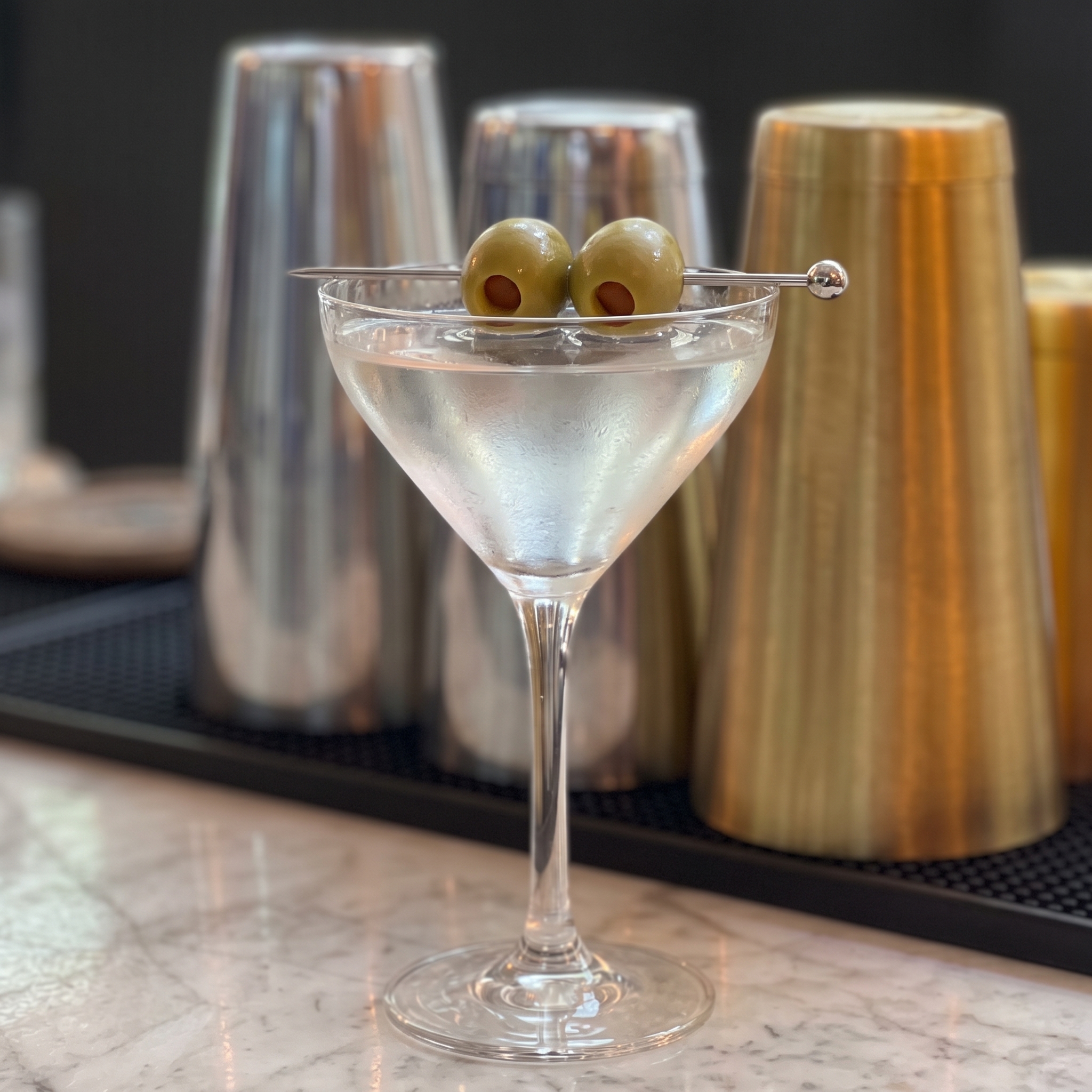 Copa Martini con un Dry Martini transparente y dos aceitunas.