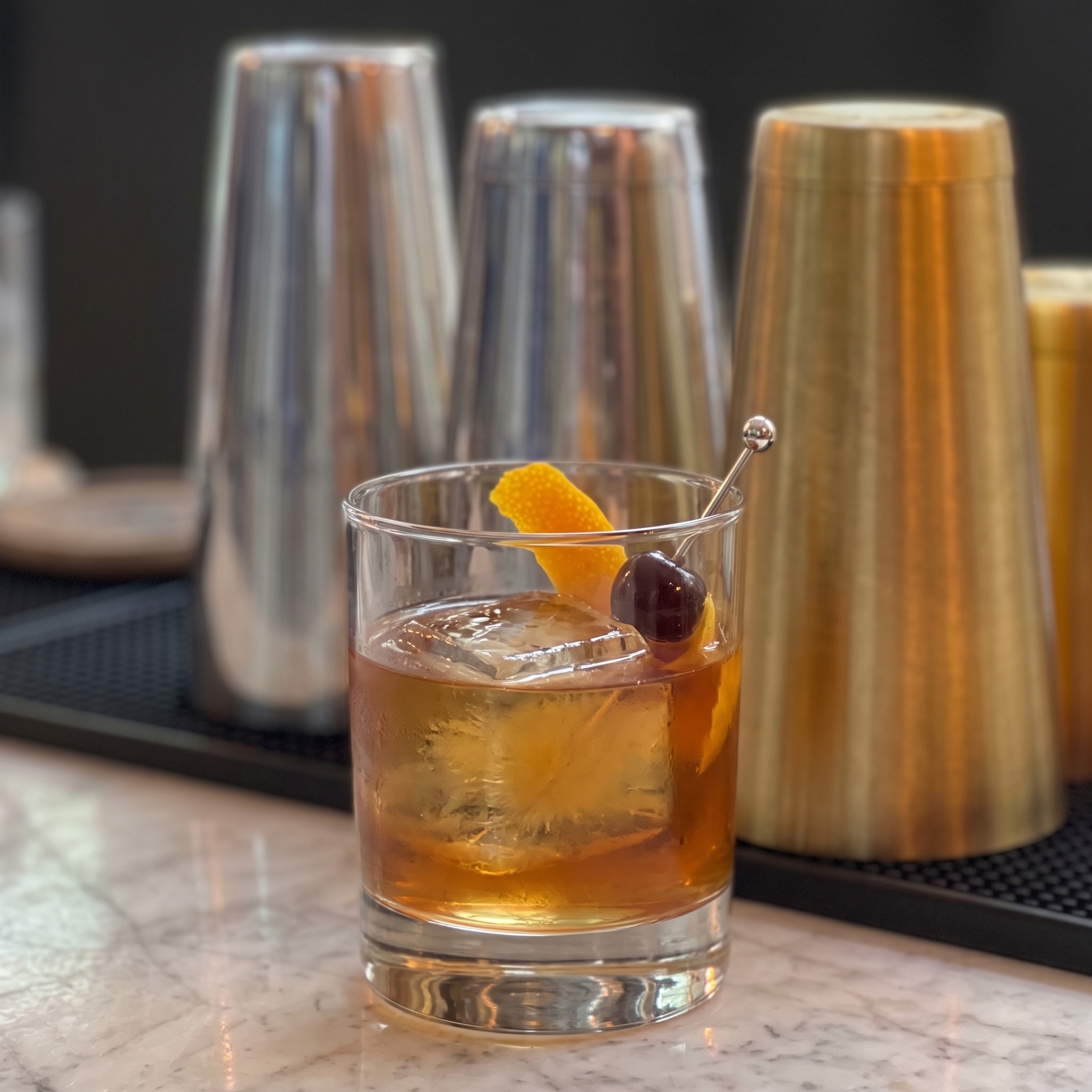 Vaso Old Fashioned con whisky, hielo y un twist de piel de naranja.