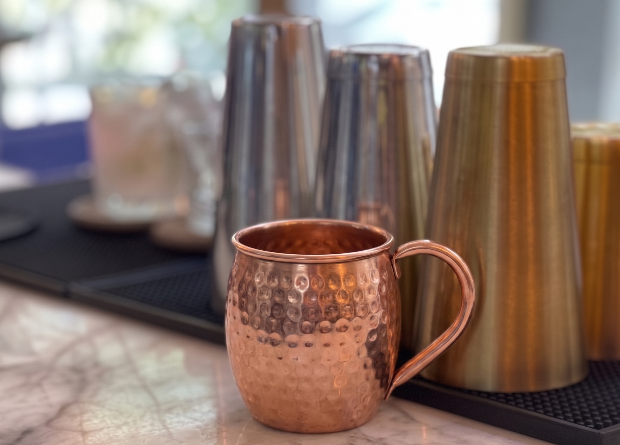 Taza metálica de cobre vacía sobre una barra.